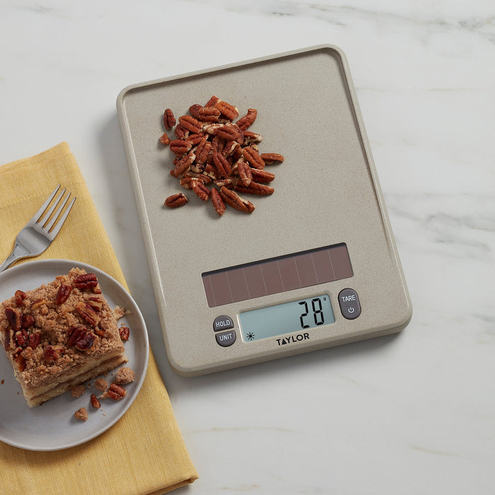 Overhead view of Taylor scale with pecans on the weighing tray beside a yellow napkin and recipe book