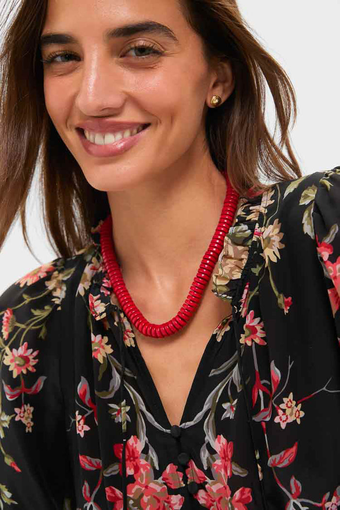 Smiling woman wearing the Barrel Red Statement Necklace, featuring vibrant red magnesite disks and gold clasp, creating an effortless, fun, and high-end look.