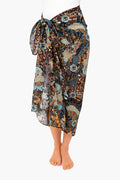 Wearing a knee-length Ulla Johnson batik sarong with a large side bow and brown, blue, and beige floral print—a stylish cotton coverup or lightweight swimwear for chic days by the water.