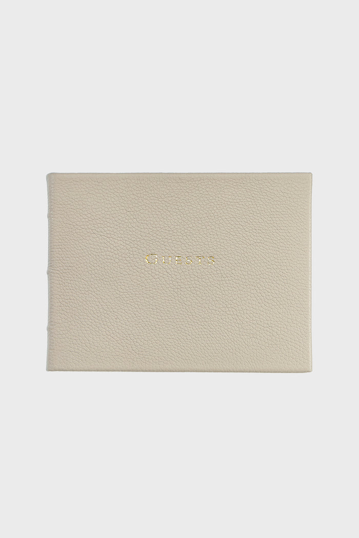 The Graphic Image beige leather guest book features "Guests" embossed in gold on the cover, highlighting their elegant handmade leather craftsmanship.