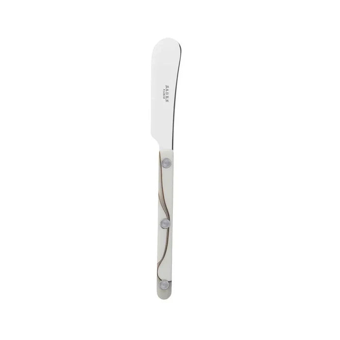The Sabre Bistrot Dune Butter Spreader Ivory features a stainless steel blade with a rounded tip and three rivets on the handle, shown against a white background—an elegant piece of French flatware.