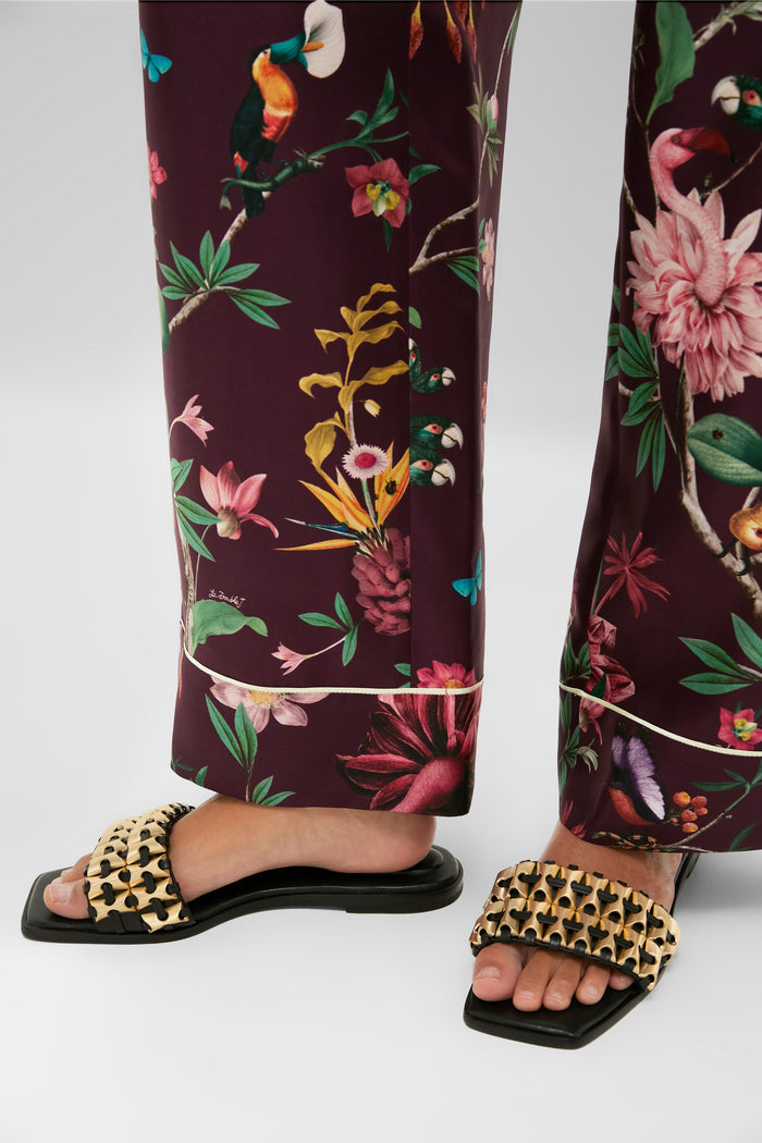 Black Faye Beaded Leather Flat Slides with a chunky gold-tone chain-link strap, embodying effortless elegance and classic style, paired with tropical-print pants for a fun, high-end look.
