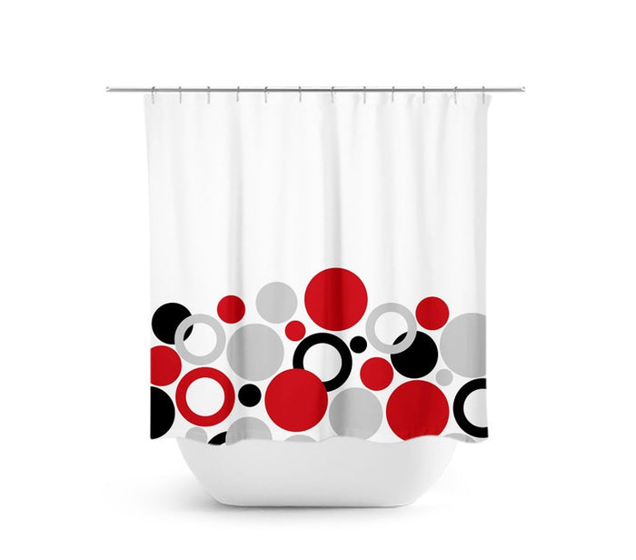 A shower curtain with a geometric pattern featuring red circles, black circles, and gray circles on a white background. The circles are like a geometric bubble bath.