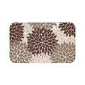 A rectangular memory foam mat with an abstract, brown, beige, and light brown floral burst pattern against a white background, and with an anti-slip backing.