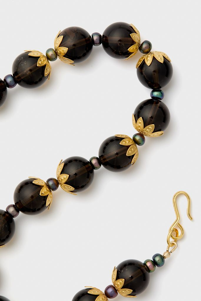 Brown Tommie Necklace: A classic, high-end necklace featuring glossy dark-smoky beads, iridescent pearls, and decorative gold-tone fittings, offering an effortless, fun touch to any ensemble.