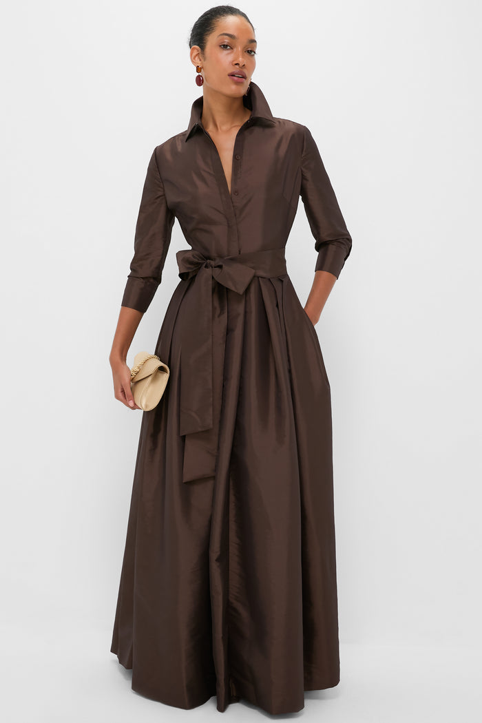 Woman in long brown shirtdress, holding soft-cream clutch, wears classic, high-end Carnelian Xiomara Earrings, adding an effortless touch of fun elegance.