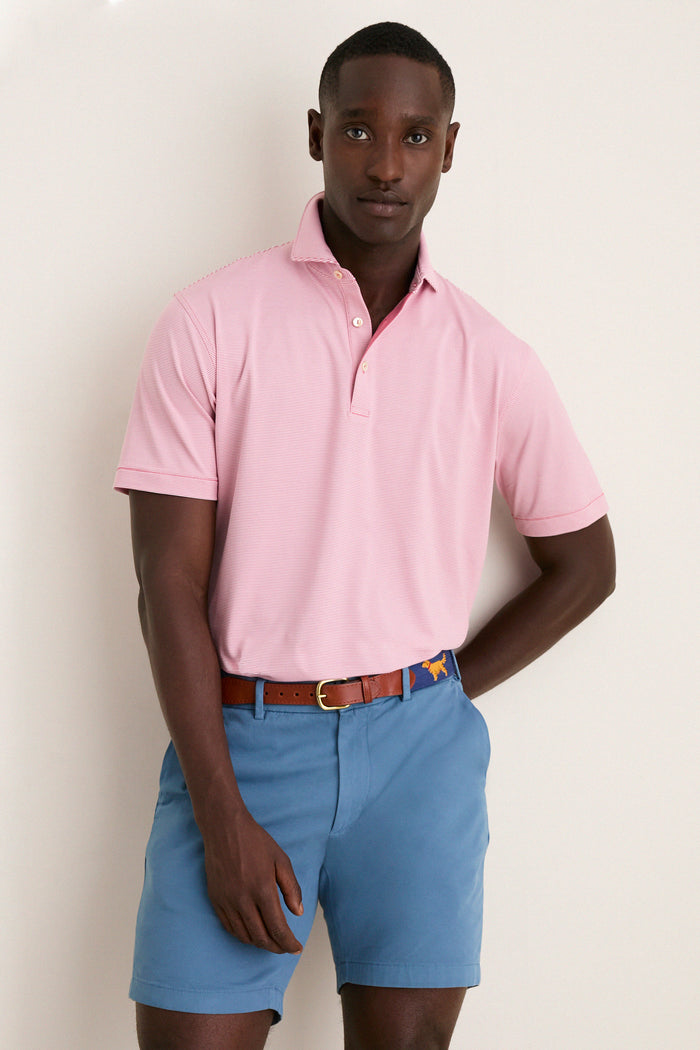 Young man in a Chili Red Jubilee Performance Jersey Polo, embodying classic, effortless style with its tailored fit and high-end, fun design, perfect for spring adventures.