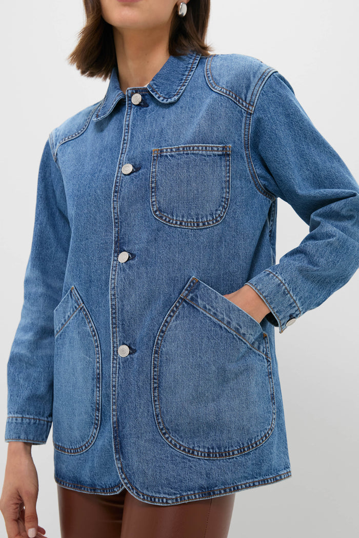 A person in a Twin Doves Denim blue vintage stonewash jacket with three front pockets and silver buttons, paired with relaxed fit brown pants.