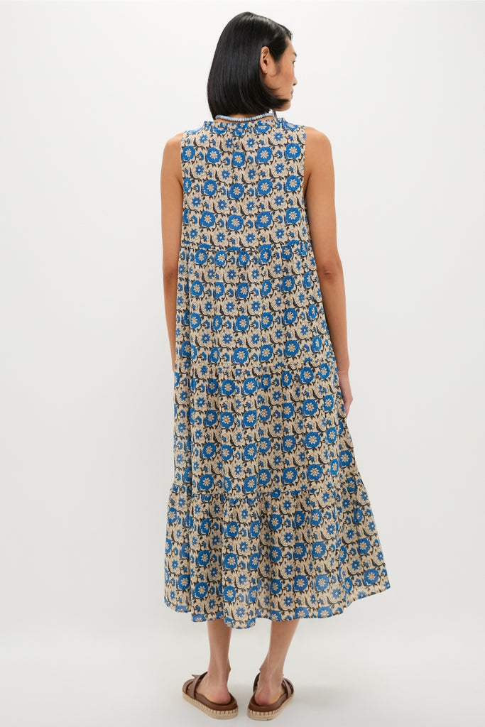Woman wearing classic Cobalt Primrose Salty Paloma Caftan, an effortless, high-end, tiered dress with blue-and-beige floral motif, standing in flat sandals.