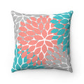 A decorative throw pillow with a floral burst design in coral, gray, and aqua colors, against a white background.