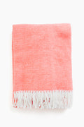 A folded Matouk coral throw made from brushed cotton, featuring white fringe trim along the edges.