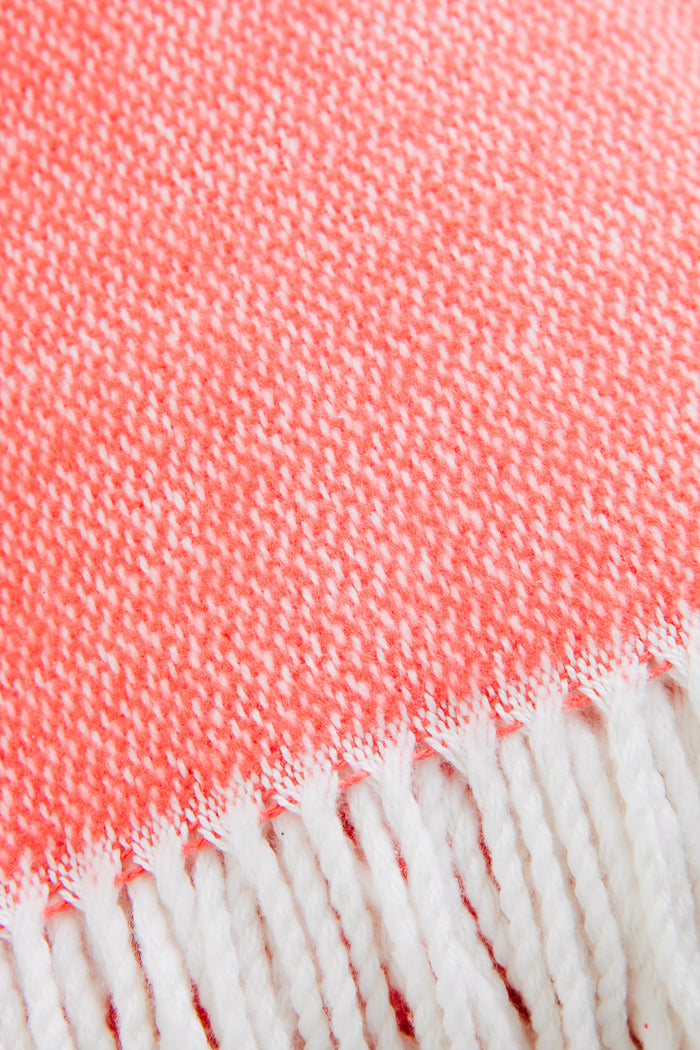 Coral Pezzo Throw with classic white fringe, effortlessly combining high-end craftsmanship and fun style in soft brushed cotton, perfect for any lounging space.
