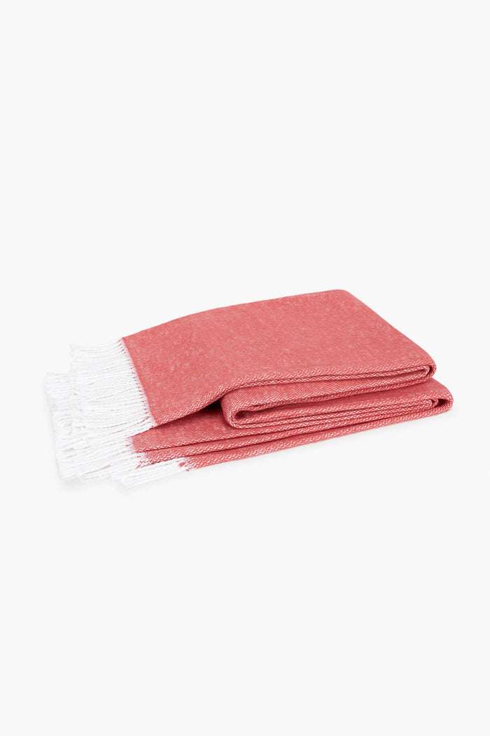 Coral Pezzo Throw: A classic, effortless woven throw blanket with a fun white tassel fringe, crafted from high-end cotton, perfect for adding warmth to any space.