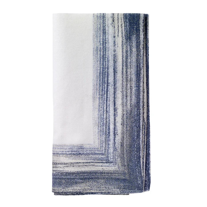 The Bodrum Cornice Napkin Navy Set of 4 features soft cotton linen napkins in white with a blue and gray gradient rectangular border along two edges.