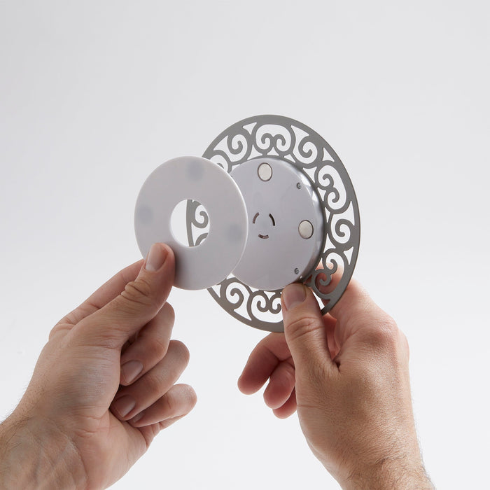 Hands assemble the decorative magnetic screen thermometer showing the ornate gray ring and white dial