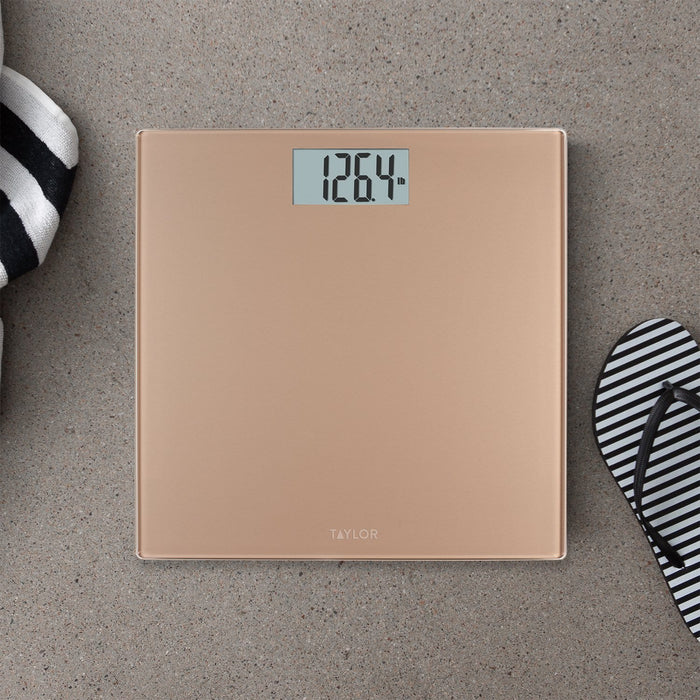Digital champagne bathroom scale on a textured floor with a striped sandal nearby