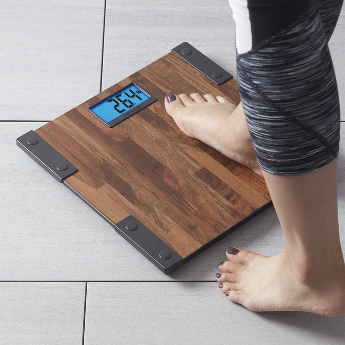 Feet on a wooden farmhouse digital bathroom scale weighing themselves on a tiled floor