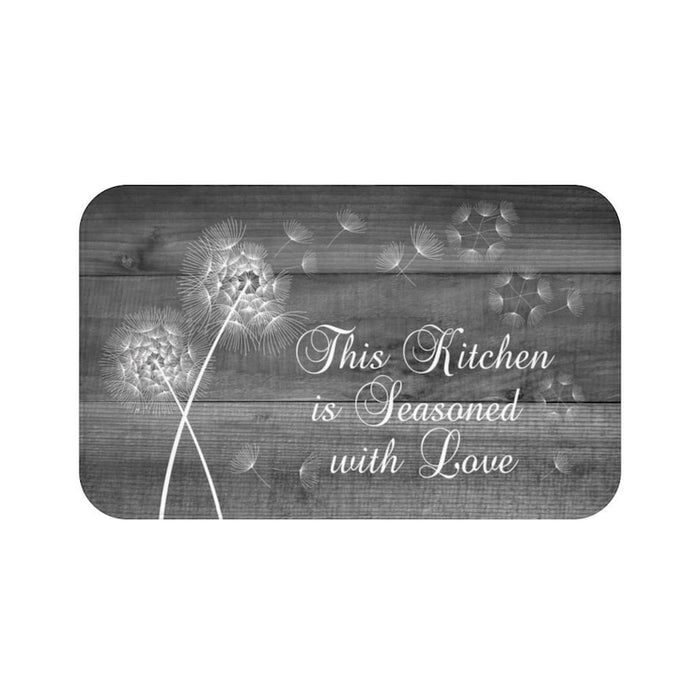 Charcoal gray background with wood board pattern. There are two dandelions  with the phrase "This Kitchen is Seasoned with Love"
