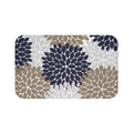 A rectangular memory foam mat with an abstract, navy blue, tan, and light gray floral burst pattern against a white background, and with an anti-slip backing.