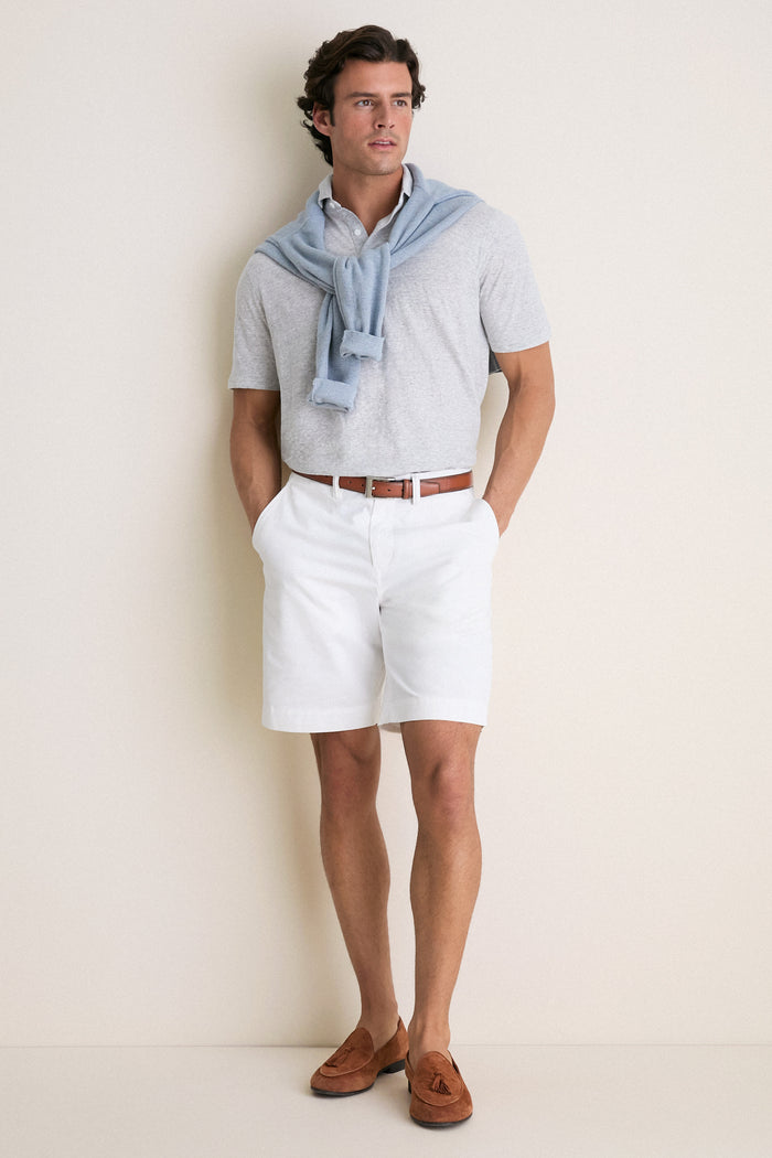 Man in Gale Gray Linen Sanibel Polo, embodying classic, effortless style. Paired with white shorts, showcasing high-end, fun fashion. Perfect for sun-soaked adventures.