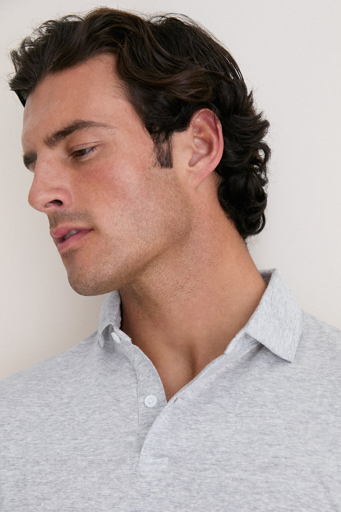 Young man in a classic, light-gray Gale Gray Linen Sanibel Polo, showcasing an effortless, high-end style with its low-profile collar and partial button placket.