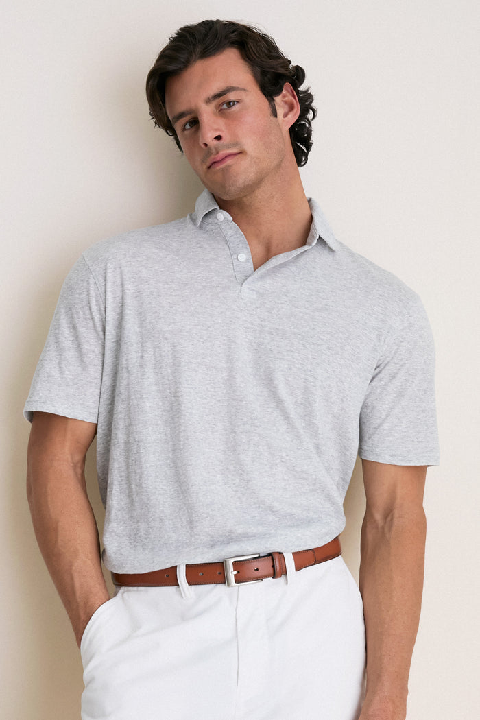 Male model wearing the Gale Gray Linen Sanibel Polo, a classic, effortless short-sleeve shirt with a partial button placket, styled with white trousers and a leather belt.