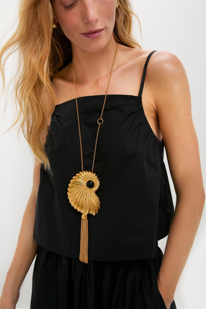 Woman wearing a classic black cami top, styled with the effortlessly high-end Gold Aveline Necklace featuring a spiral pendant and tasseled fringe, embodying fun elegance.