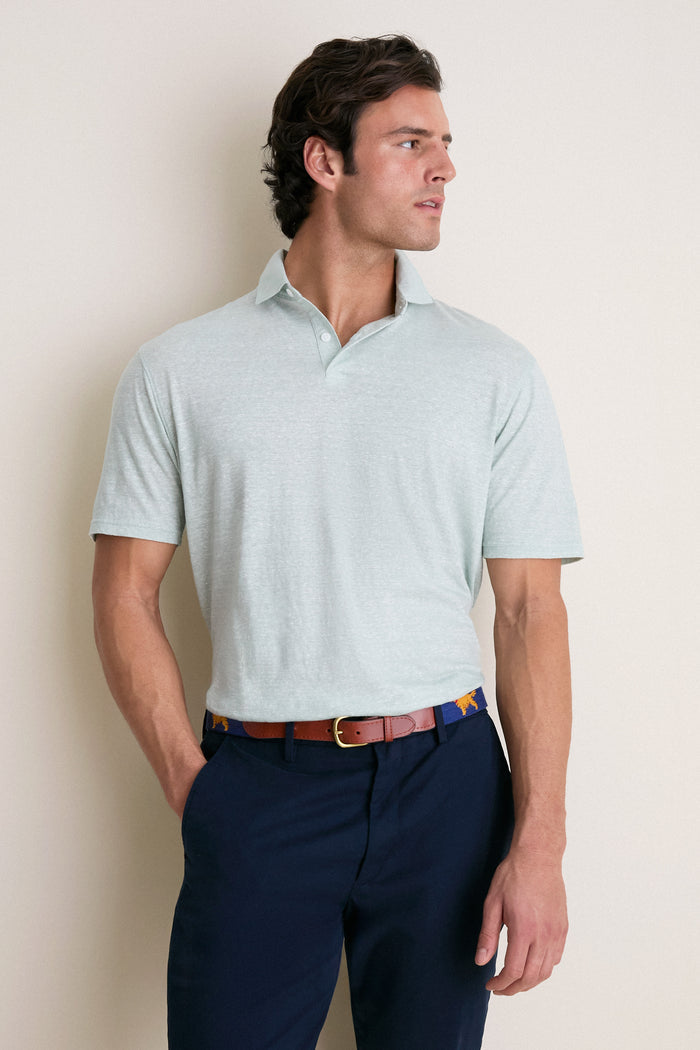 Young man in a classic Grandview Linen Sanibel Polo, effortlessly styled with navy trousers and a unique belt, embodying high-end, fun, and confident casual wear.