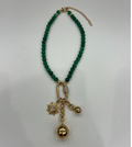 A Tuckernuck Vintage Accessories beaded green necklace with a gold chain extension, featuring three gold pendants—a sun, ball, and clear crystal on a metal ring.