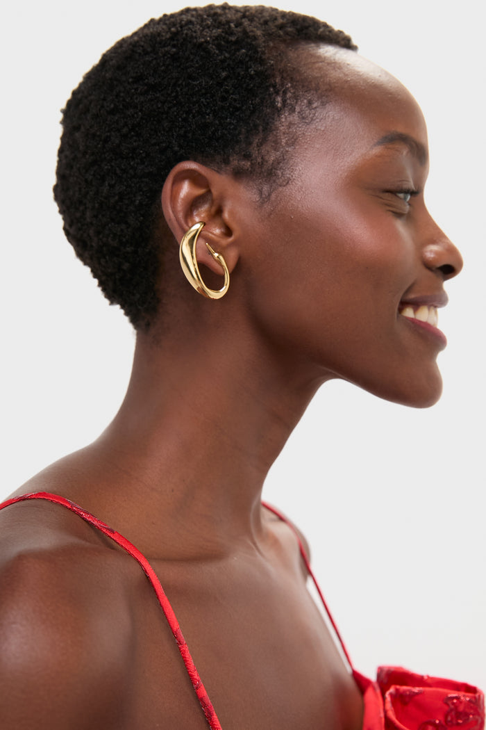 Young woman wearing High Polish Gold Egret Climber Earrings, showcasing an effortless, high-end style. The sculptural gold design adds a classic, fun touch to her look.