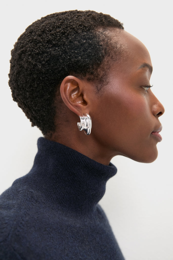 Classic High Polish Silver Leona Hoops with organic grooves, worn effortlessly with a navy turtleneck, exuding a fun, high-end style.