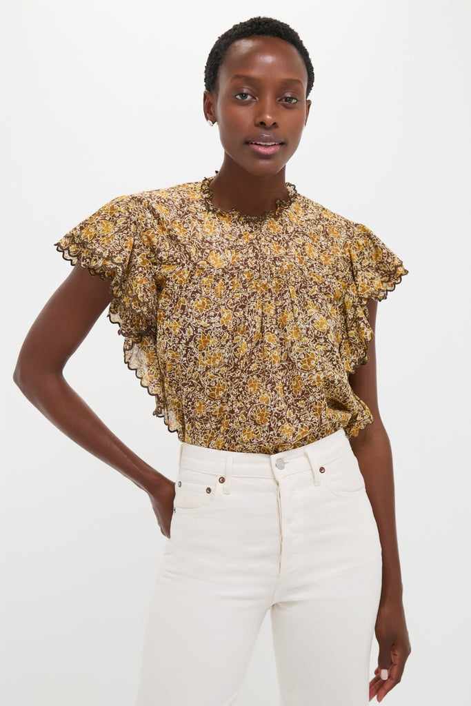 Woman wears Khaki Daliyane Top, a classic, ruffled blouse, tucked into high-waisted jeans, embodying an effortless, fun, high-end style.