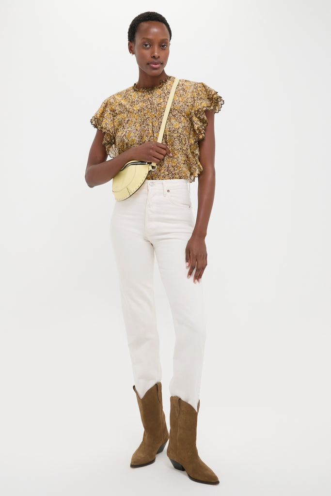 Model wearing the Khaki Daliyane Top, a classic, effortless ditsy floral blouse, paired with high-waisted white jeans and tan cowboy boots, showcasing a fun, high-end style.
