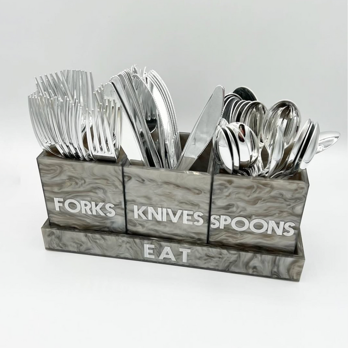The Eye Candy Let's Eat Silverware Caddy Grey Marble features chic marble patterns and three labeled sections—FORKS, KNIVES, SPOONS—with "EAT" on the base, keeping utensils stylishly organized against a plain white background.