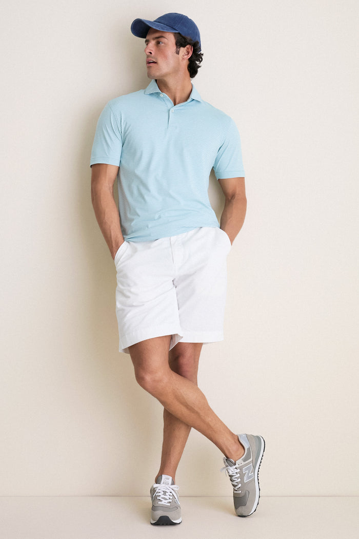 Man in classic, effortless Light Willow Ballad Performance Jersey Polo poses casually, showcasing its high-end, fun design with tailored fit and technical fabric.