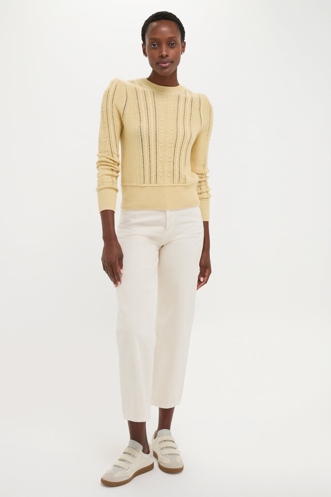 Model wearing the classic Light Yellow Kalyn Sweater, showcasing an effortless, fitted silhouette with cable-knit detailing, paired with chic, cropped jeans and fun, high-end sneakers.