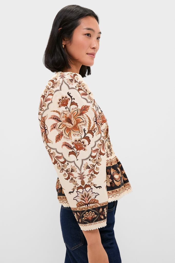 Young woman in side-profile wearing the Majestic Garden Sand Blouse, showcasing its classic, effortless vintage floral pattern, paired with dark blue jeans for a high-end, fun look.