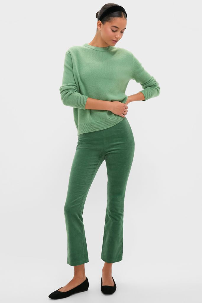 Woman models the Meadow Green Cashmere Boyfriend Bodie Crewneck Sweater, paired with high-waisted flared pants, embodying a classic, effortless, and high-end style.