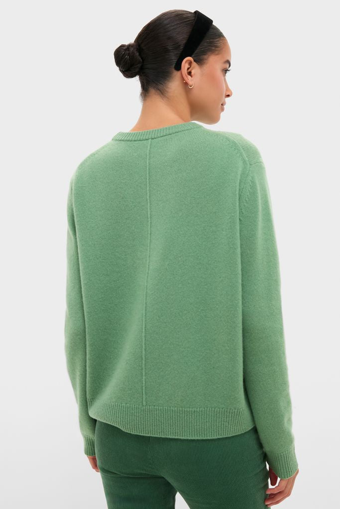 Woman in a classic Meadow Green Cashmere Boyfriend Bodie Crewneck Sweater, showcasing its elegant vertical seam, paired effortlessly with corduroy trousers for a high-end, fun look.