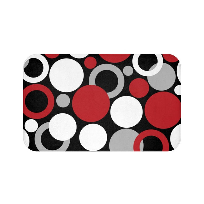 A rectangular memory foam mat with a geometric circles, rings, and dots pattern in white, gray, and red against a black background.