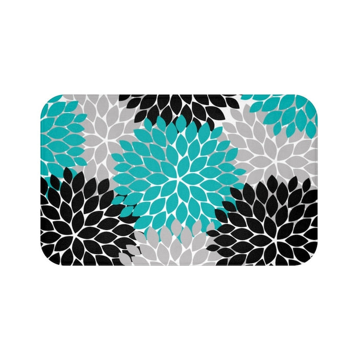 A rectangular memory foam mat with an abstract floral burst pattern in teal, black, and gray colors against a white background, featuring an anti-slip backing.