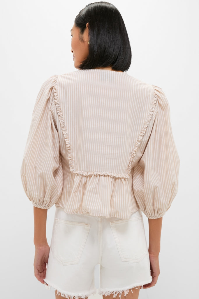 Back view of a person in a classic Natural Stripe Stevie Blouse with voluminous sleeves and ruffle trim, paired with high-waisted shorts for an effortless, high-end look.