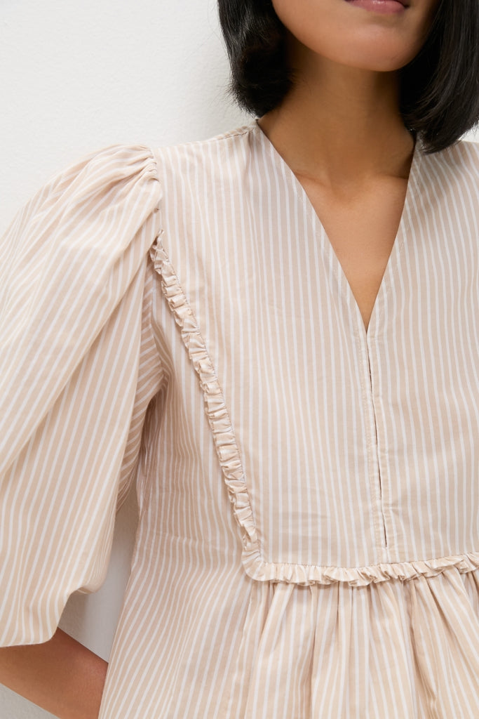 Natural Stripe Stevie Blouse with classic pinstripes, effortless ruffle trim, and fun puff sleeves, embodying a high-end, cool style. Perfect for versatile, relaxed elegance.