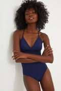 A woman with curly hair stands confidently with arms crossed, wearing a Vineyard Vines Sconset One Piece in Nautical Navy.