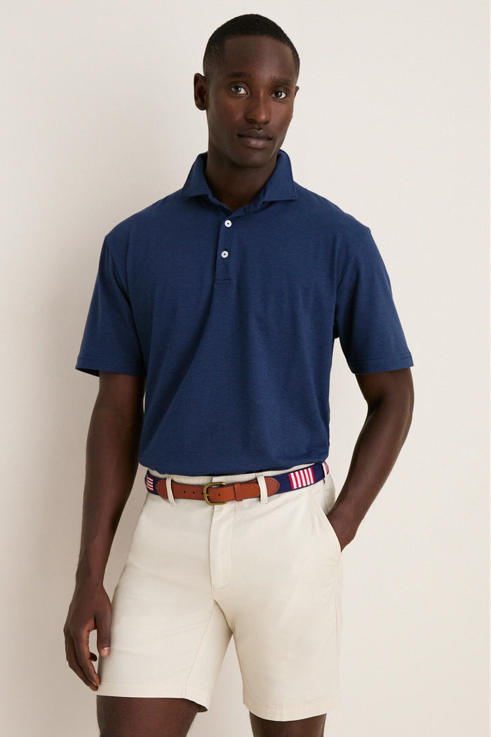 Young man models the Navy Ryles Crown Flex Cotton Polo, showcasing its classic cutaway collar and effortless, high-end style, paired with beige chino shorts and a striped belt.