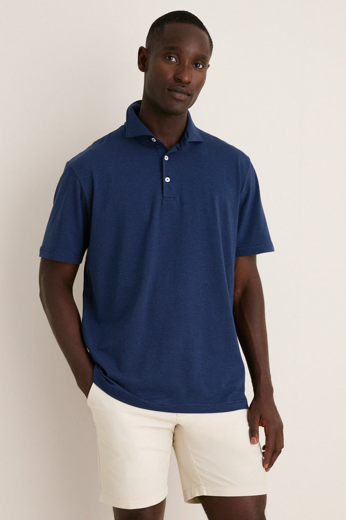 Man wearing the Navy Ryles Crown Flex Cotton Polo with classic cutaway collar and beige shorts, embodying effortless, high-end style perfect for fun, casual occasions.