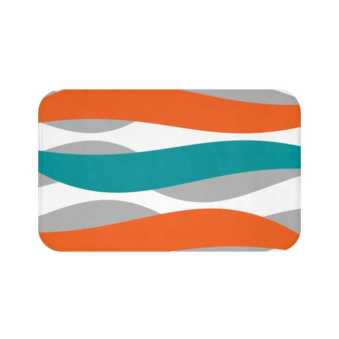 A rectangular memory foam mat with an orange, teal, and gray geometric pattern and anti-slip backing.