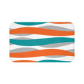 abstract wave pattern in orange, teal, and light gray against a white background on a memory foam mat