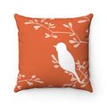 A square decorative throw pillow with an orange background, featuring a white love bird perched on a branch with off-white branches in the background.