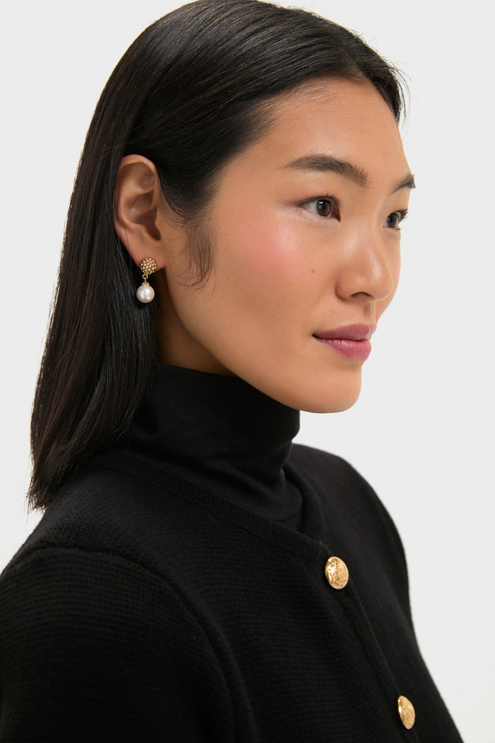Woman wearing classic Pearl Berry Drop Stud Earrings, featuring a textured gold stud and dangling pearl, paired with an effortless black turtleneck and cardigan ensemble.